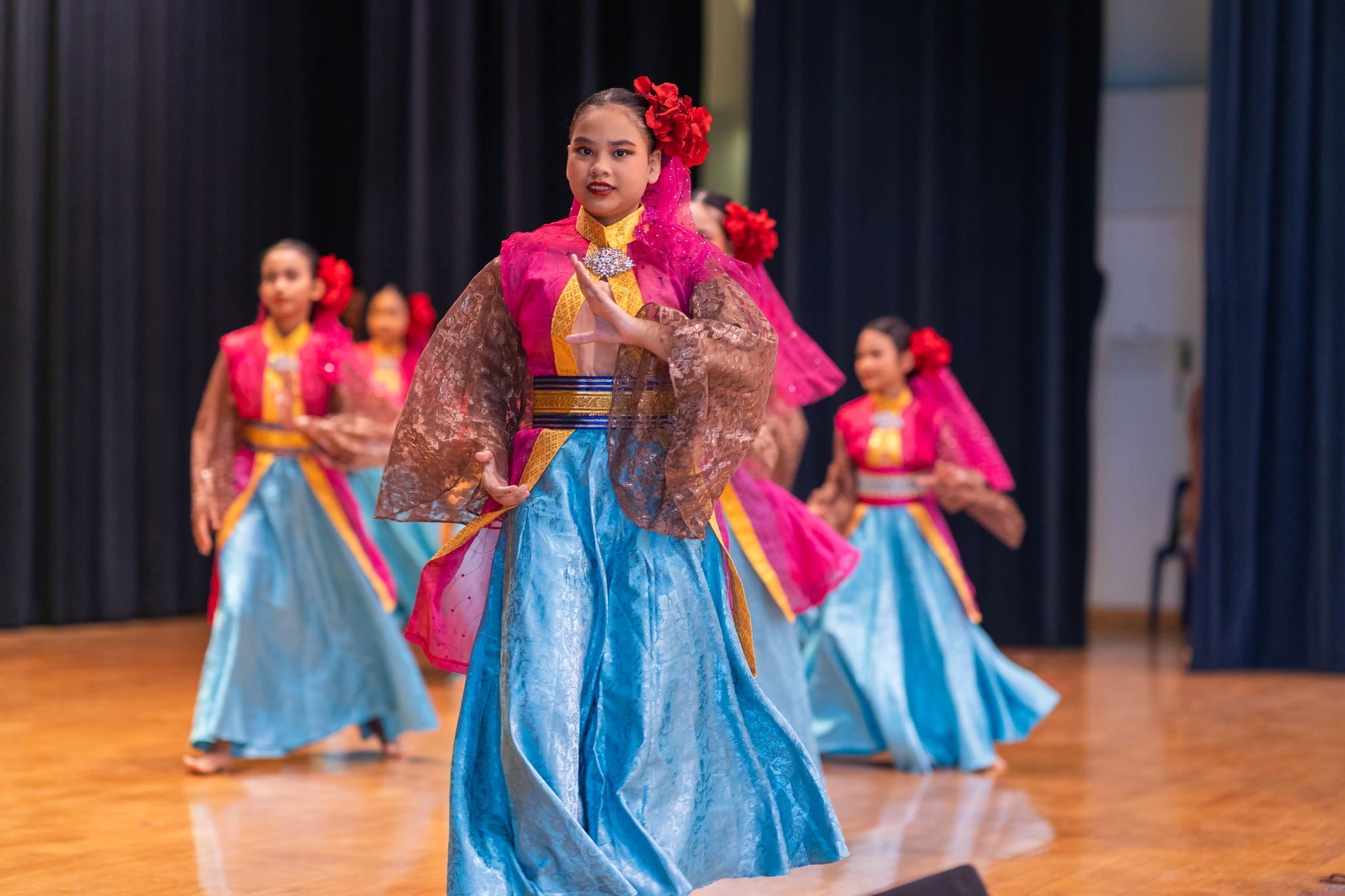 Students in traditional Malay costumes doing a dance routine